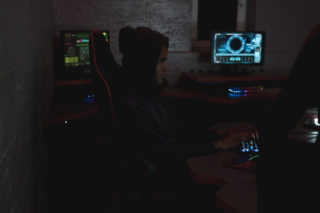 A professional analyzing data on multiple monitors in a dark room, highlighting cybersecurity themes.